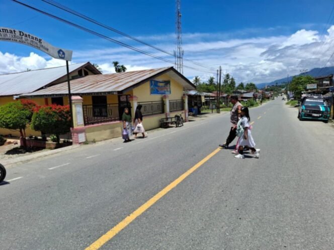 
					Personil kapolsek Bambel membantu anak sekolah menyeberangi di jalan Kutacane-Medan.